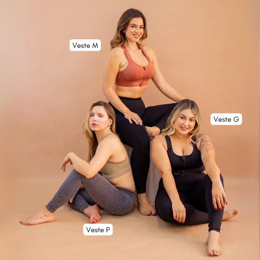 Três mulheres com diferentes biotipos vestindo sutiãs esportivos Cygnuss em tamanhos P, M e G, destacando a diversidade de modelagem e ajuste do produto. Fundo bege neutro enfatizando os detalhes das peças e o conforto do design.