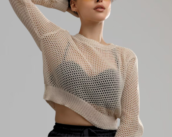 Mulher usando sutiã preto à mostra sob blusa transparente de trama larga, mostrando tendência de lingerie como peça principal do look.