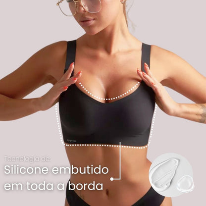 Imagem em close do Sutiã Premium Reforçado Cygnuss na cor bege, com modelo segurando o tecido para demonstrar a suavidade e elasticidade do material.