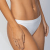 Close frontal da calcinha fio Cygnuss x Lupo na cor branca, vestida por modelo real. Com laterais médias e acabamento sem costura, a peça oferece ajuste perfeito, toque suave e conforto invisível sob qualquer roupa.