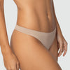 Close frontal da calcinha fio Cygnuss x Lupo na cor nude, vestida por modelo real. A peça tem laterais médias, acabamento sem costura e tecido em microfibra que garante toque macio, caimento discreto e conforto no dia a dia.
