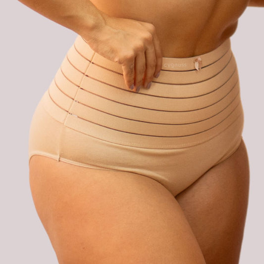 Imagem de mulher usando a Calcinha Modeladora Model - Seca Barriga, em tom bege. A peça de alta compressão tem faixa com listras horizontais, proporcionando controle da barriga e modelagem eficiente da silhueta.