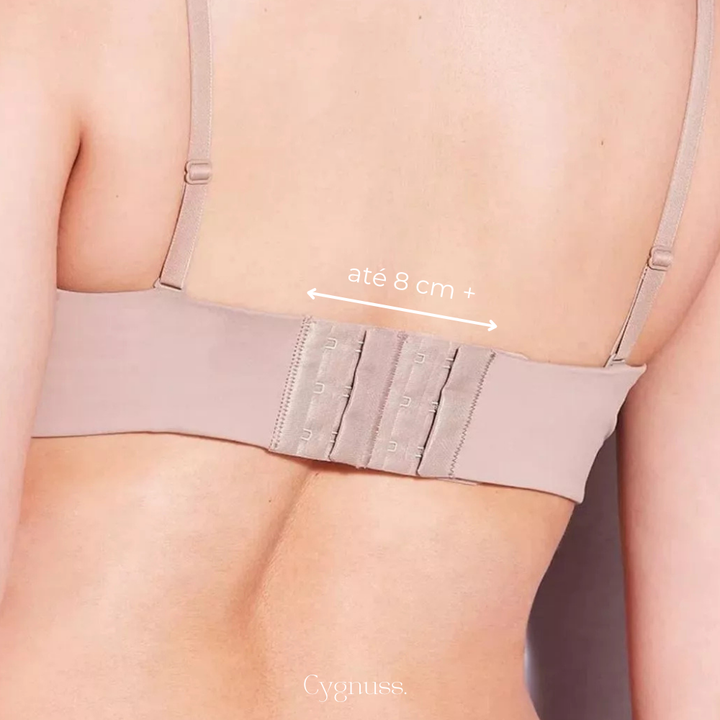 Close das costas de uma mulher usando extensor de sutia bege com tres niveis de regulagem. O acessorio esta conectado ao fecho original do sutia, proporcionando ate 8 cm extras de ajuste para maior conforto. Ideal para ampliar o uso de pecas apertadas sem perder sustentacao.