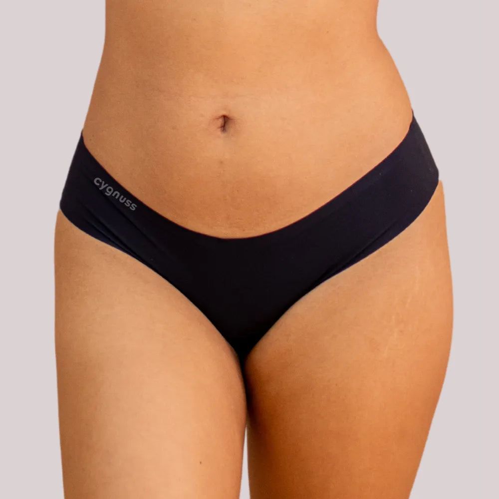 magem frontal da região do quadril de uma mulher usando uma calcinha preta fio-dental sem costura da Cygnuss. O design ajusta-se ao corpo com conforto e discrição.