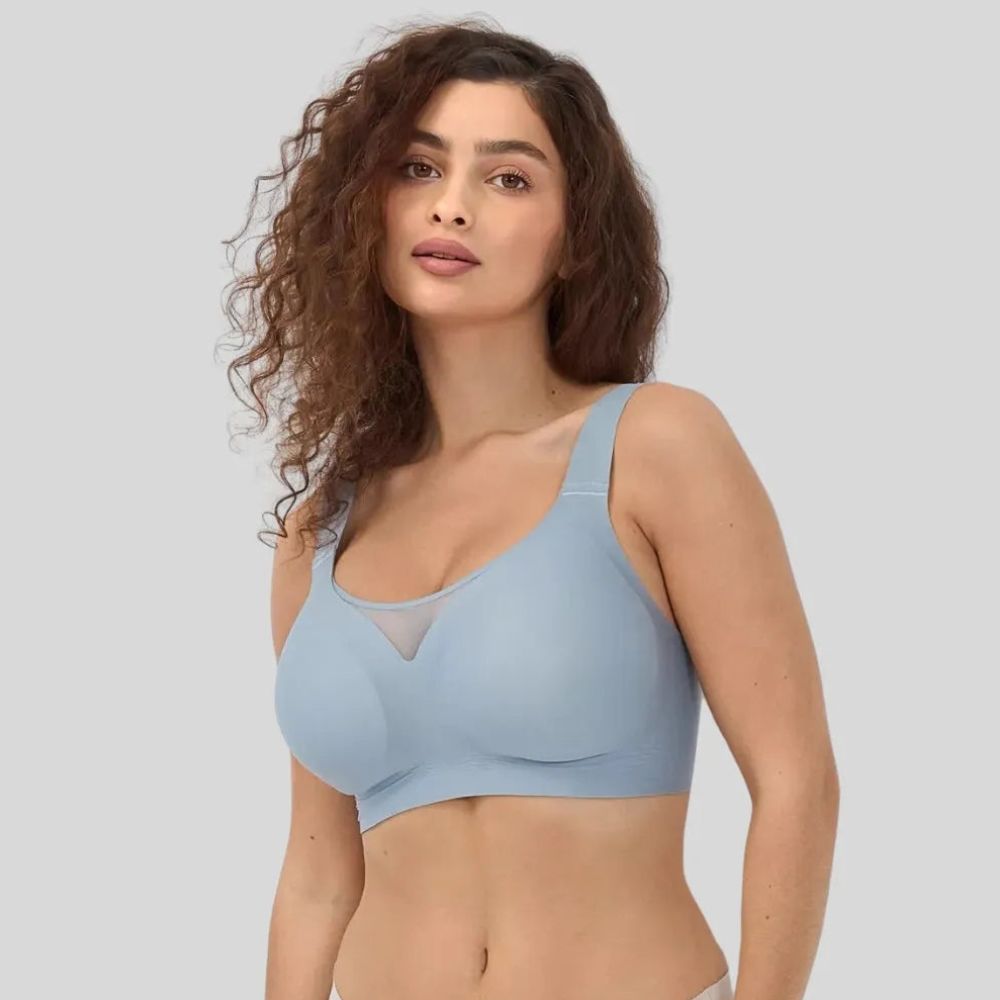 Mulher de cabelos cacheados vestindo o sutiã azul Cygnuss, destacando o bojo moldado, alças largas e o detalhe em tule no decote para um toque sofisticado e confortável.