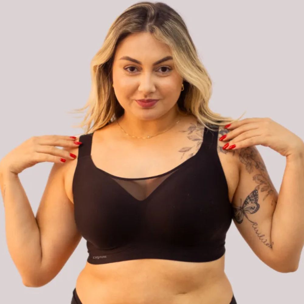 Mulher com corpo real vestindo o sutiã preto da Cygnuss, destacando o design confortável, as alças largas e o detalhe em tule no decote para um toque elegante.
