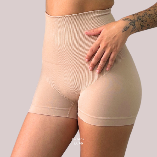 Vista frontal lateral do Short Slim Modelador Cygnuss x Lupo na cor bege, evidenciando a compressão na região abdominal, acabamento sem costuras e cintura alta que modela sem apertar.