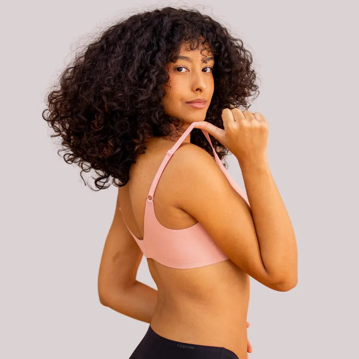 Woman wearing pink sutiã sem aro, showcasing adjustable alças finas for comfort and style, ideal for discreet wear.