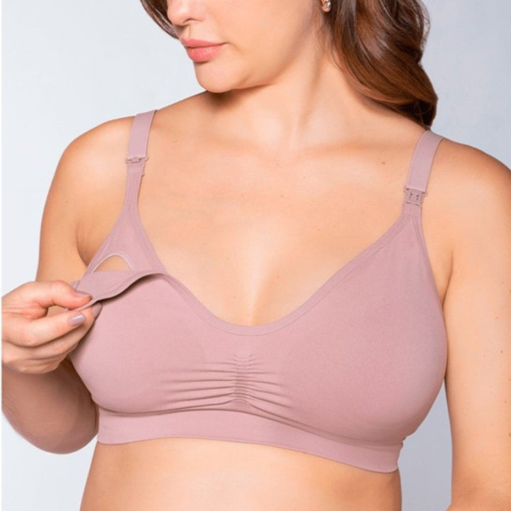 Mulher vestindo o Sutiã Amamentação sem Bojo na cor rosa antigo da collab Cygnuss x Lupo. O modelo possui alças reguláveis com clipes para facilitar a amamentação. A modelo está demonstrando a funcionalidade destacando a abertura frontal do sutiã. A peça é sem bojo, com leve franzido no centro do busto para melhor ajuste e conforto.