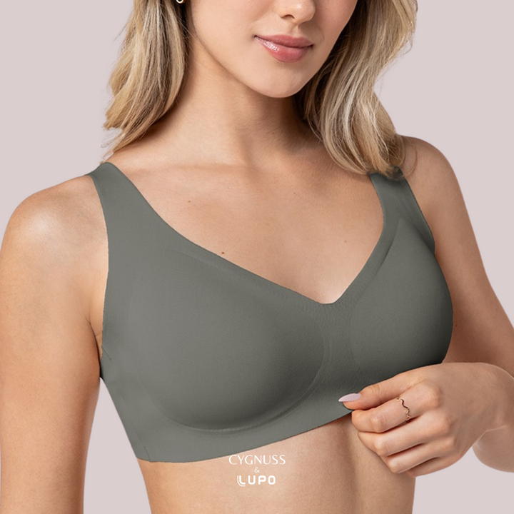 Mulher vestindo um sutiã sem costura em tom acinzentado, com alças largas e modelagem perfeita. O tecido suave e sem marcas garante conforto absoluto. O logotipo da Cygnuss & Lupo está visível na parte inferior da peça.