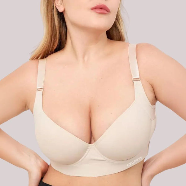 Mulher vestindo o Sutiã ElevaTop – Super Sustentação Cygnuss na cor bege. O modelo possui bojo estruturado com efeito push-up, alças largas reguláveis e base reforçada para maior firmeza. O logotipo “cygnuss” aparece discretamente na lateral inferior da peça.
