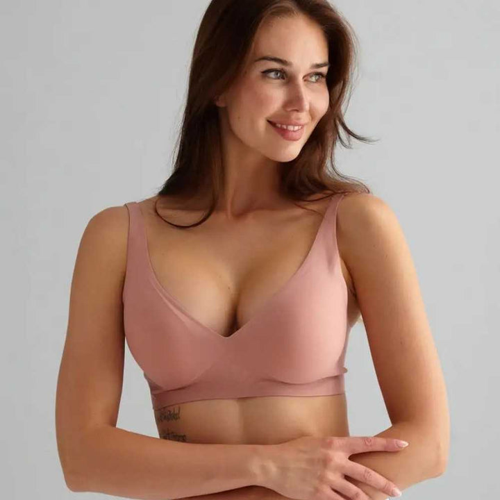 Mulher sorrindo e com as mãos cruzadas à frente do corpo, vestindo o Sutiã FIT na cor rosé. O modelo possui alças finas, bojo removível e acabamento sem costuras, oferecendo conforto, sustentação e um visual moderno.