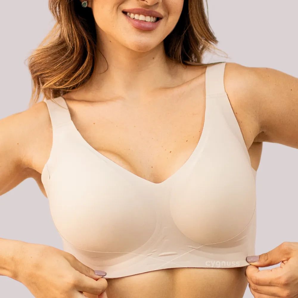 Modelo sorrindo enquanto veste o Sutiã Curves Sem Aro da Cygnuss na cor bege. A peça destaca alças largas, tecido sem costura e modelagem anatômica que oferece sustentação e conforto sem apertar.