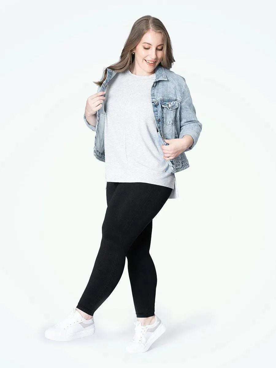 Mulher plus size sorrindo, usando a Legging Jade Fit Modeladora de Cós Alto na cor preta, combinada com camiseta cinza e tênis branco, destacando o conforto e o estilo da peça no visual casual.