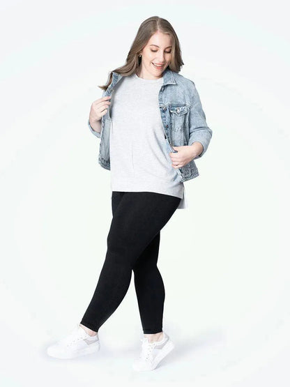 Mulher plus size sorrindo, usando a Legging Jade Fit Modeladora de Cós Alto na cor preta, combinada com camiseta cinza e tênis branco, destacando o conforto e o estilo da peça no visual casual.