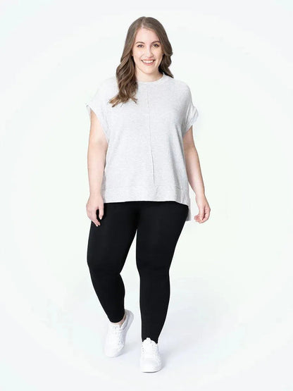 Mulher plus size sorrindo, usando a Legging Jade Fit Modeladora de Cós Alto na cor preta, combinada com camiseta cinza e tênis branco, destacando o conforto e o estilo da peça no visual casual.

